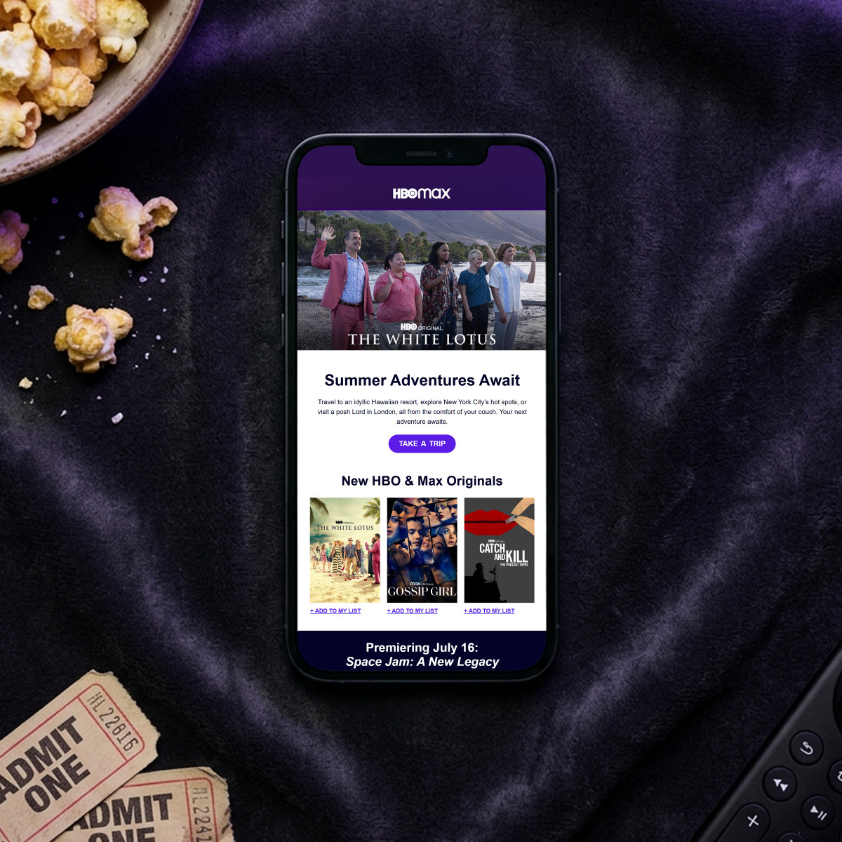 HBO Max newsletter email on a phone, beside popcorn, cinema tickets and a TV remote